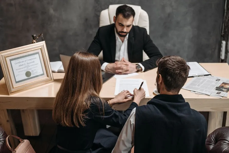Two people in a consultation meeting with an attorney across a desk, illustrating an initial legal consultation